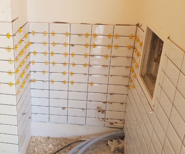 Pose de carrelage mural avec croisillons, chantier de rénovation intérieure à Royan